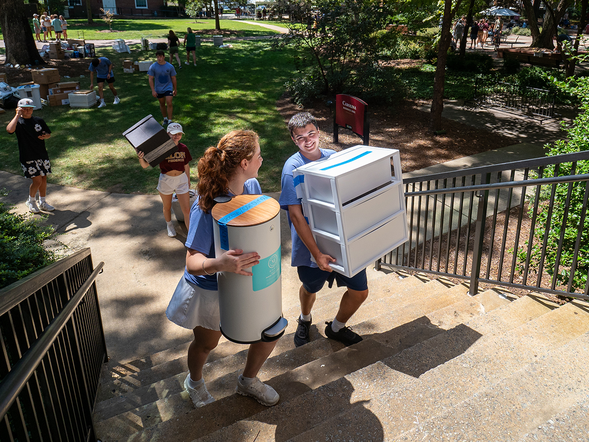 Two people carry items up stairs