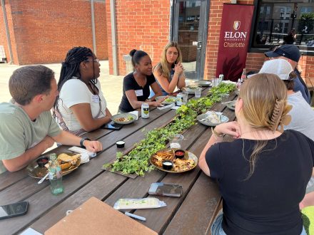 Elon students sit around a picnic table and talk