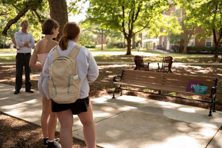 Two students look at memorial bench