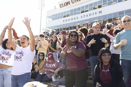 A group of people cheer at Elon Homecoming