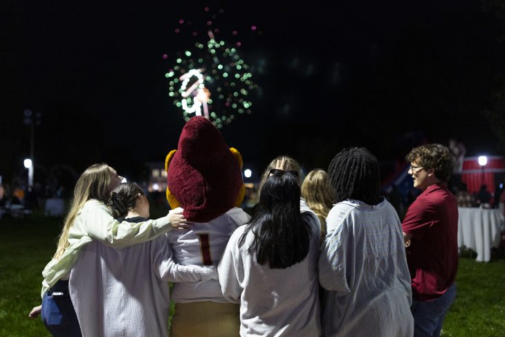 Group of people watch fireworks with Elon mascot