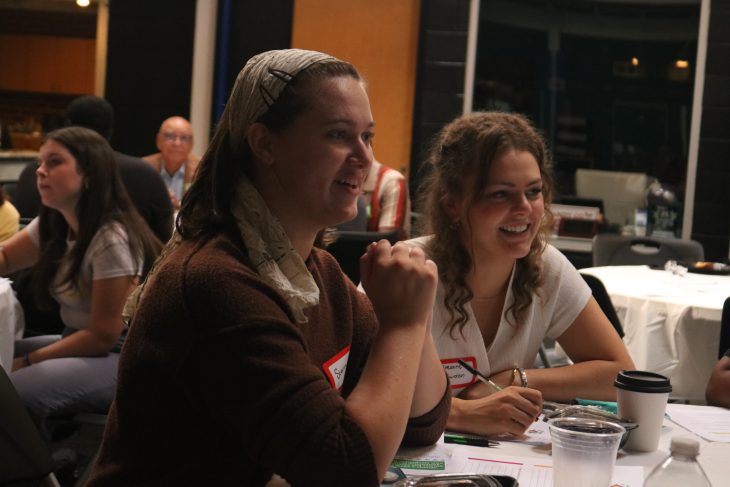 A person smiles while sitting at a table