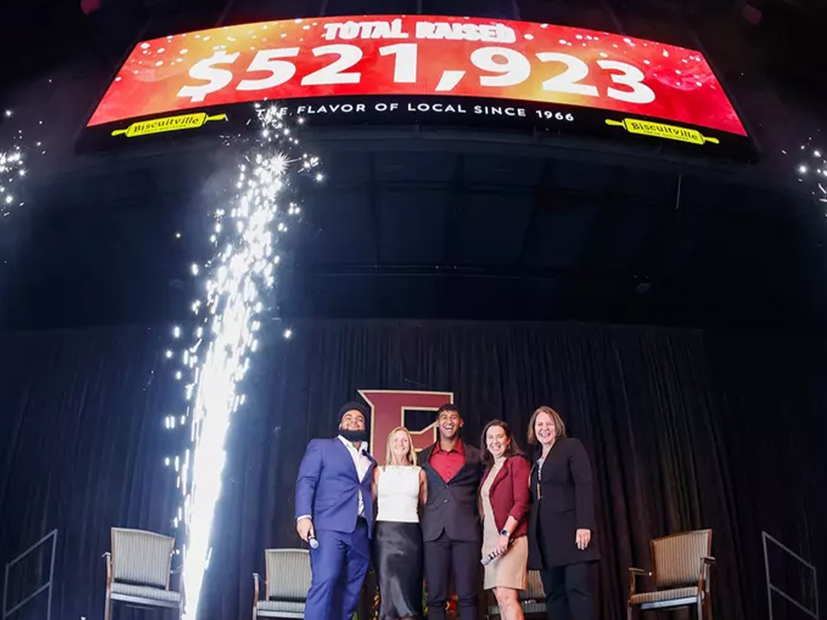 Four people stand under sign that says 