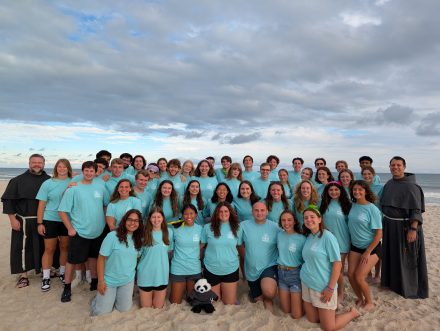 People in blue shirts pose on a beach