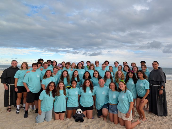 People in blue shirts pose on a beach