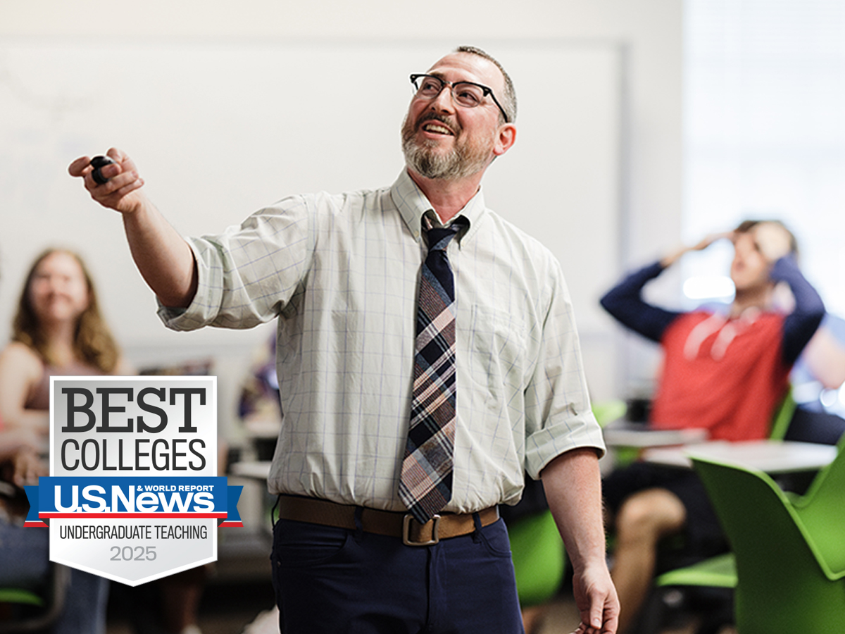 A teacher in a classroom with a U.S. News badge