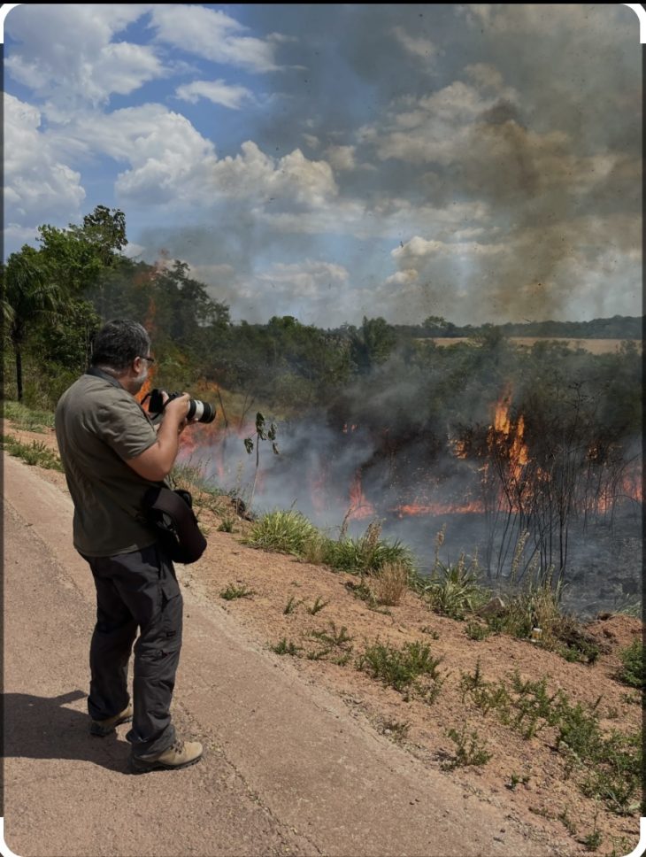 Man stands with camera by wildfire