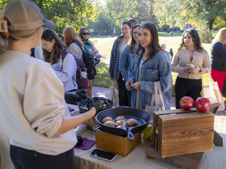 Person talks to vendor at food table.