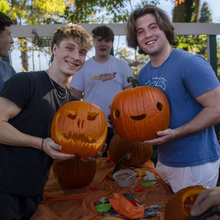 Two people hold carved pumpkins