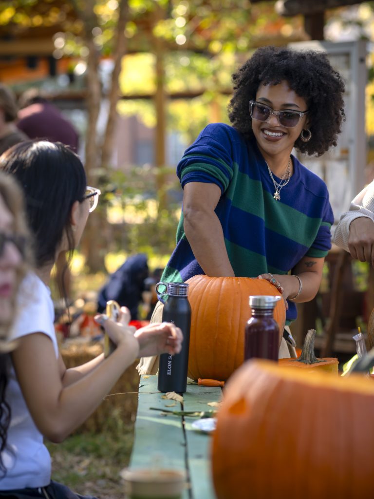 Person has hand in pumpkin and smiles