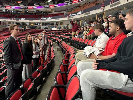 Elon students sit in Lenovo Center seats and listen.