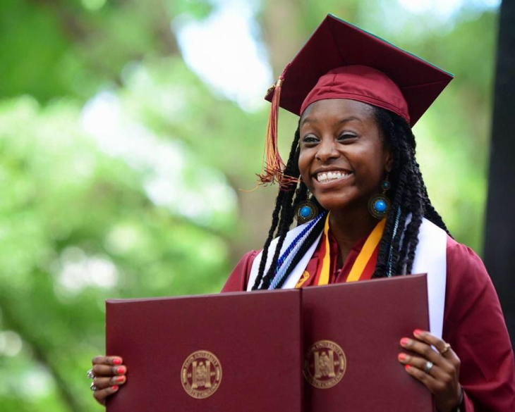 Danielle Biggs in cap and gown with diplomas