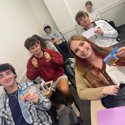 Elon students hold up Get Out to Vote postcards.