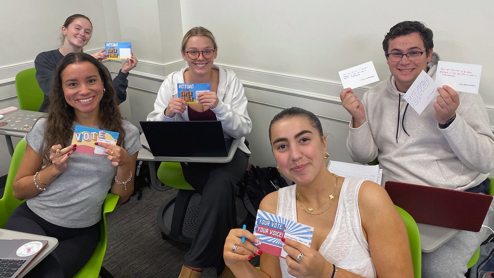 Elon students hold up Get Out to Vote postcards.