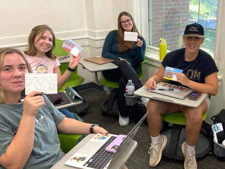 Elon students hold up Get Out to Vote postcards.