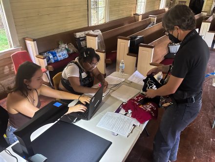 students at a table with computers process documents