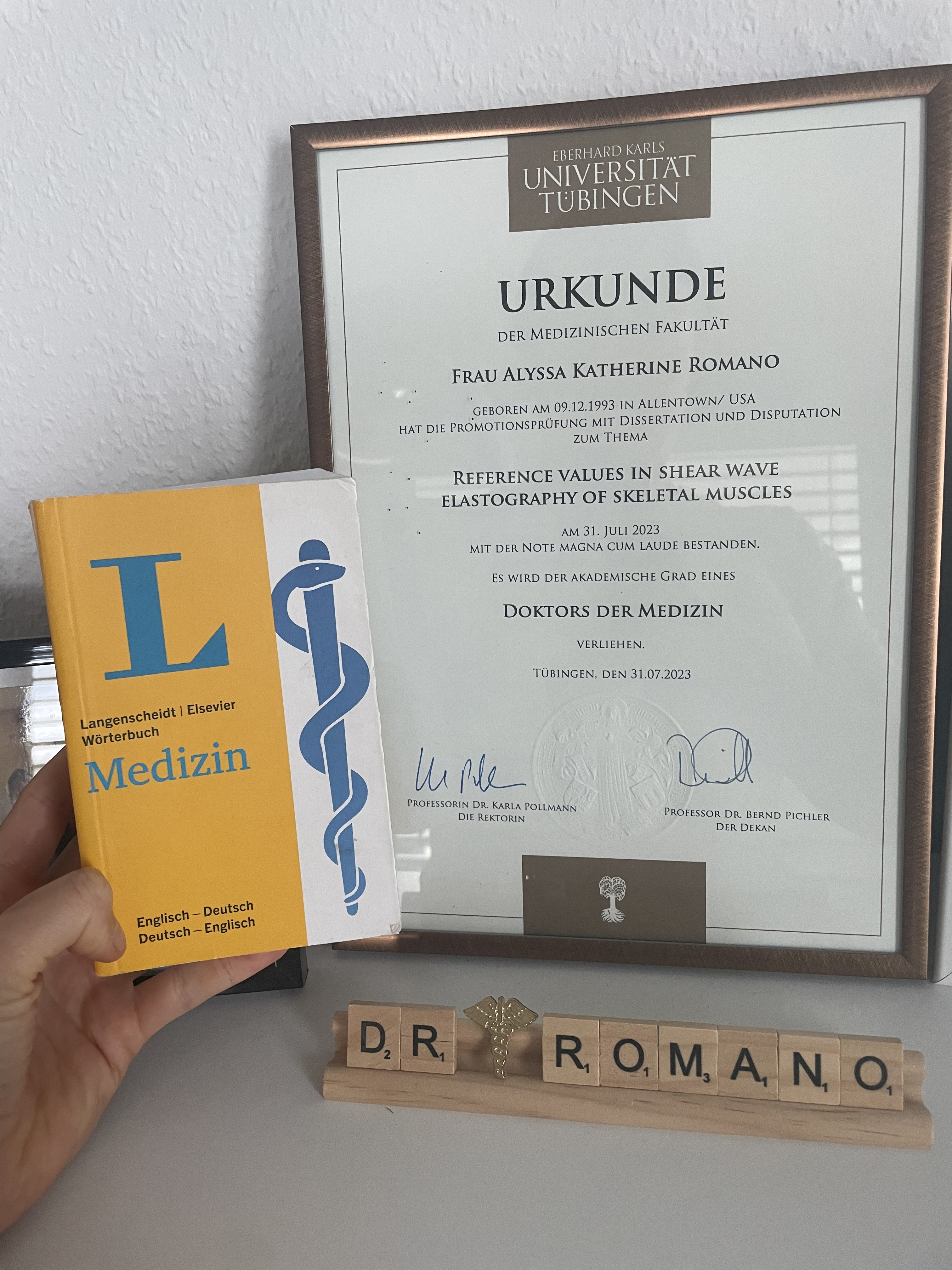 a yellow english-to-german medical dictionary and a medical degree on a shelf