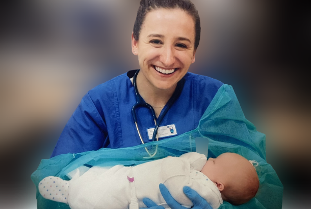 a woman in scrubs holds an infant in a hospital