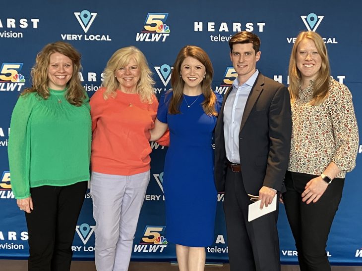 A group of Stutz's friends and family stand before a WLWT backdrop.