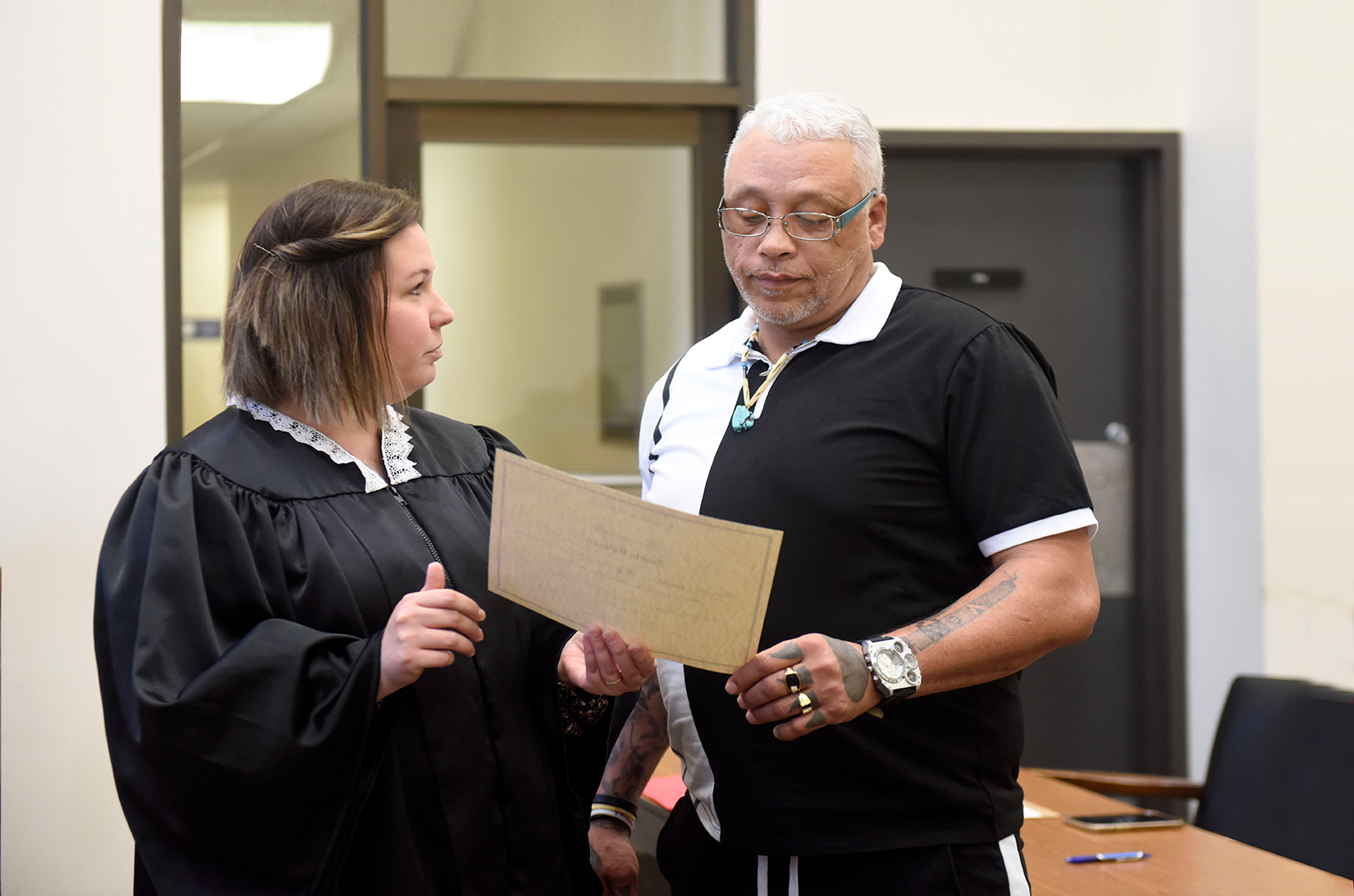 A female judge presents a man with a certificate