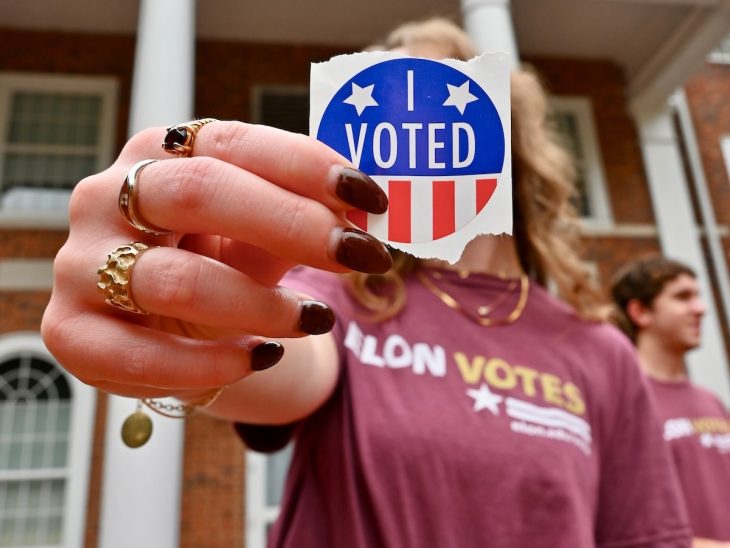 A hand holding an "I Voted" sticker