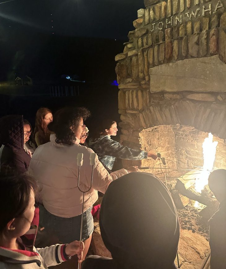 People standing around a campfire and roasting marshmallows