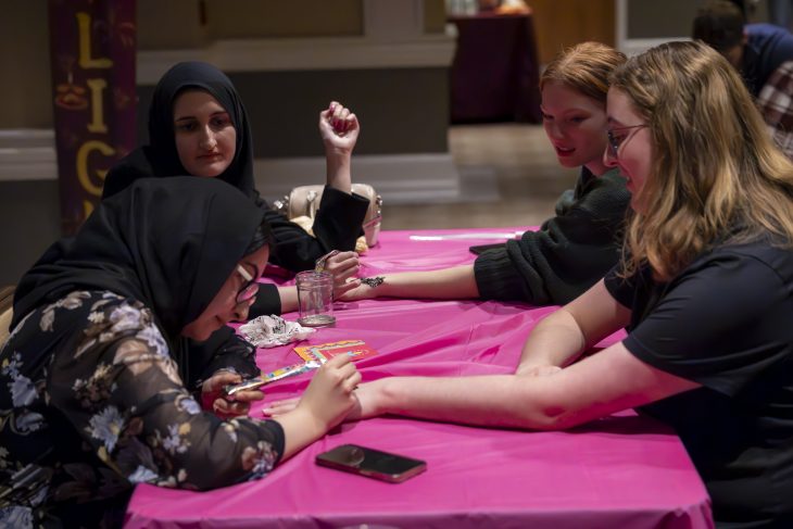 Two people paint henna art on two other people