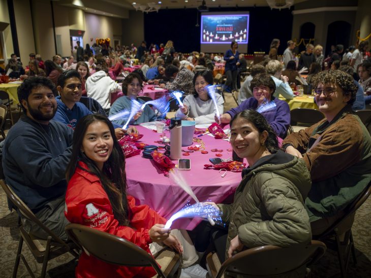 People sit around a table and smile at camera