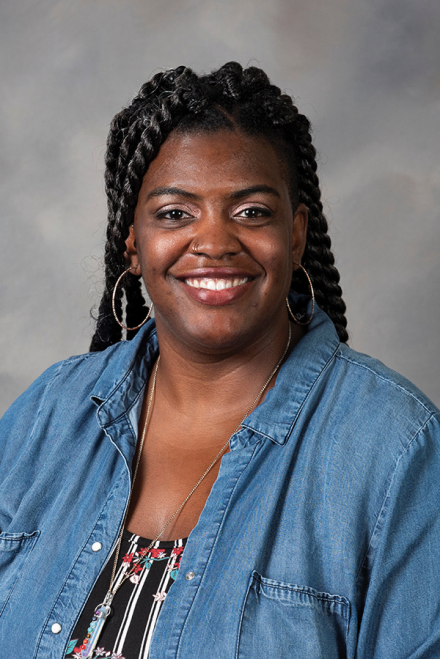 A female faculty member smiles at the camera in a directory headshot