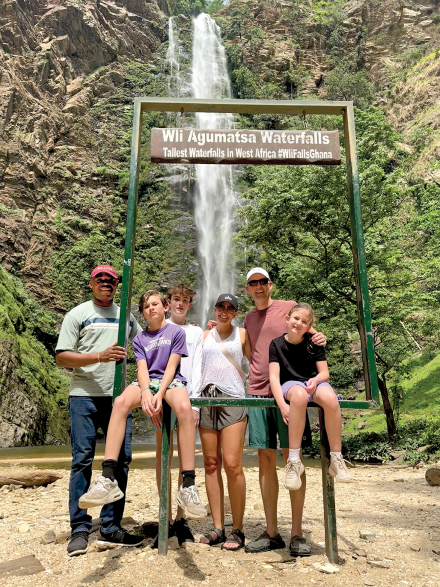 A family of five pose with their travel guide in front of Wli Falls, West Africa’s largest waterfall 