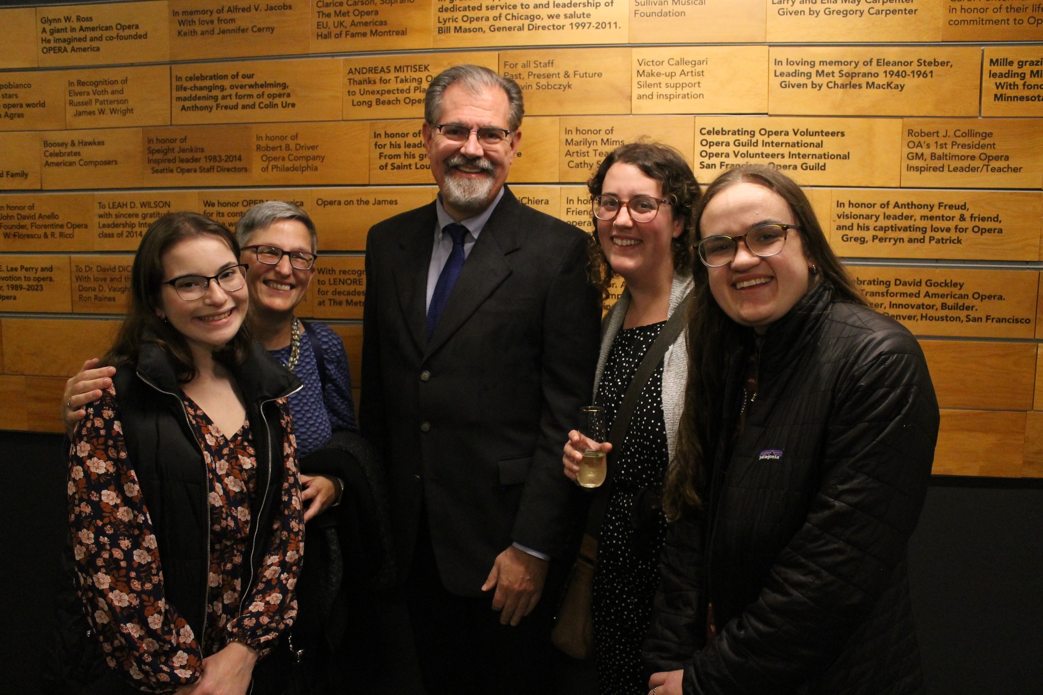 four women and a man pose for a photo in a theater lobby