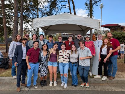 group of students and Father Peter in front of the tailgate