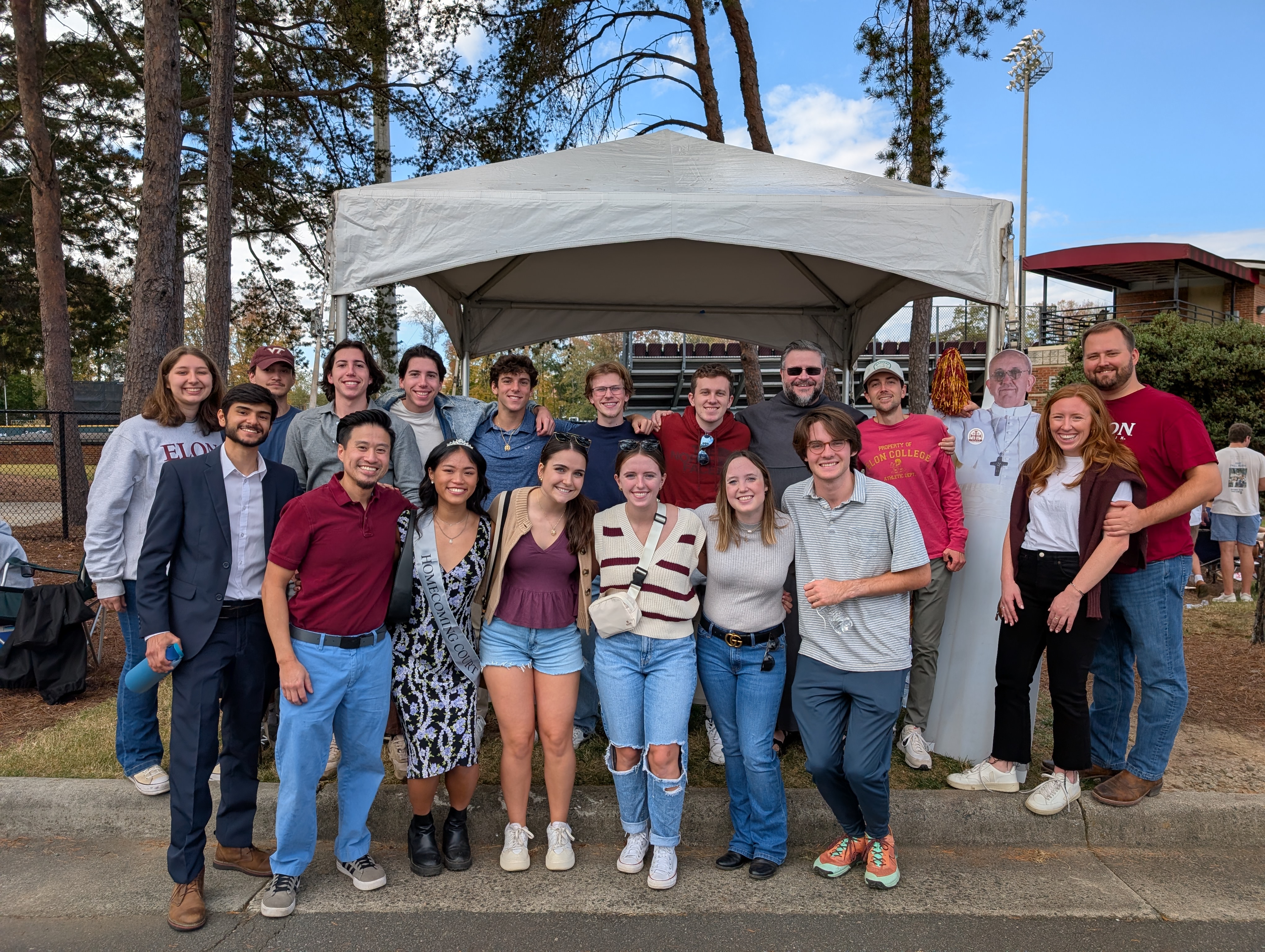 group of students and Father Peter in front of the tailgate