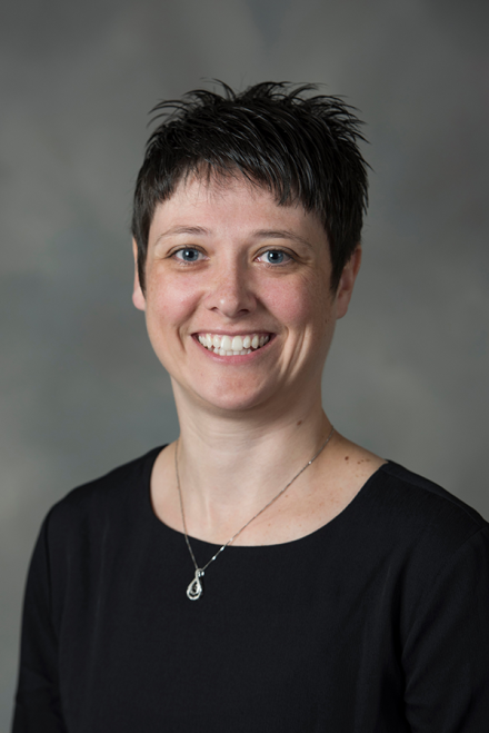 A female faculty member smiles at the camera in a directory headshot