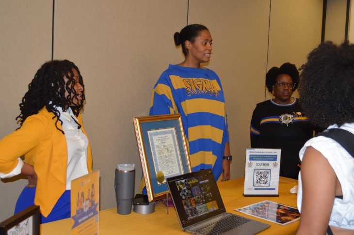 Three women stand behind a table