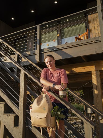 A woman stands on the stairs of her sustainable house in Elon's EcoVillage