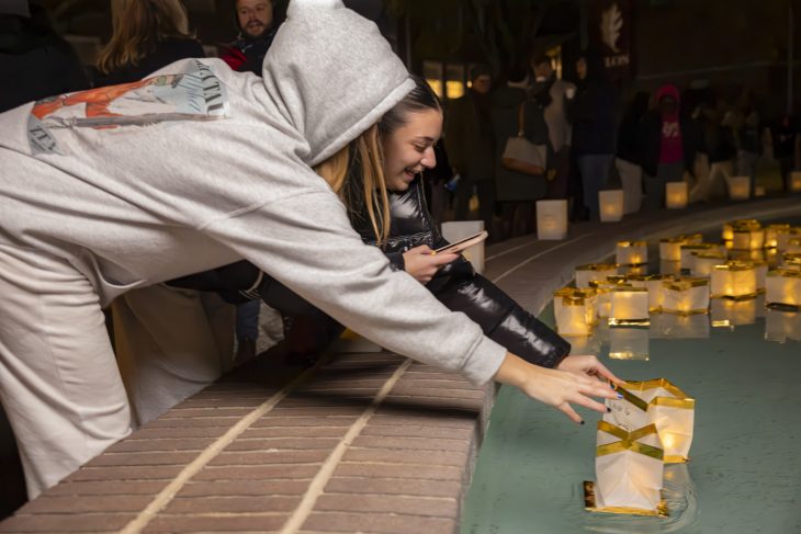 Two people touch lanterns in a fountain