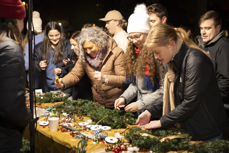 Several people make wreaths at a table