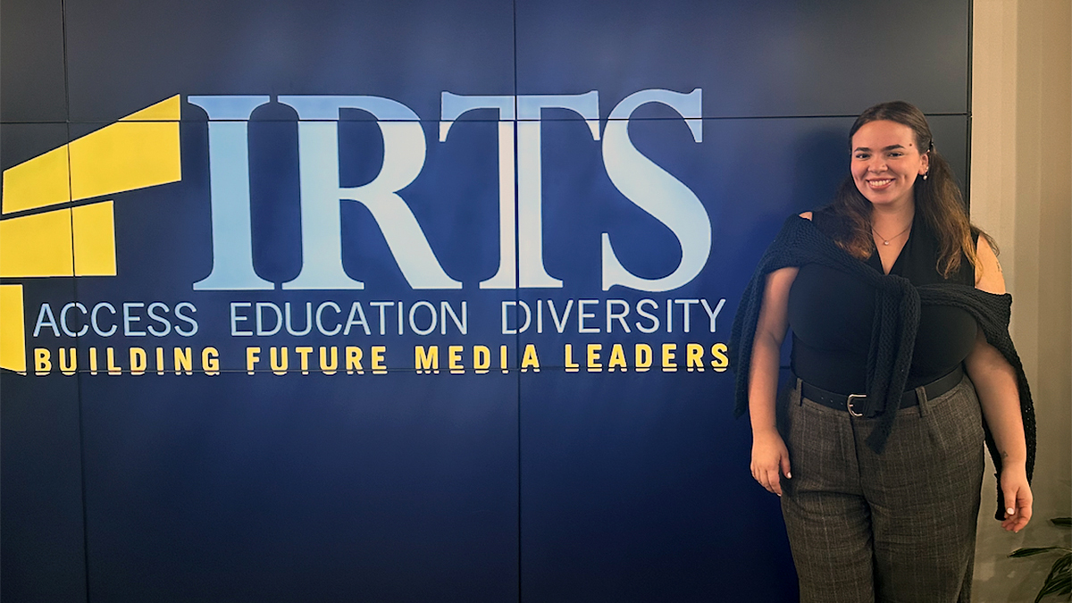 Cristy Mariné of Elon University stands before branding for the International Radio & Television Society Foundation