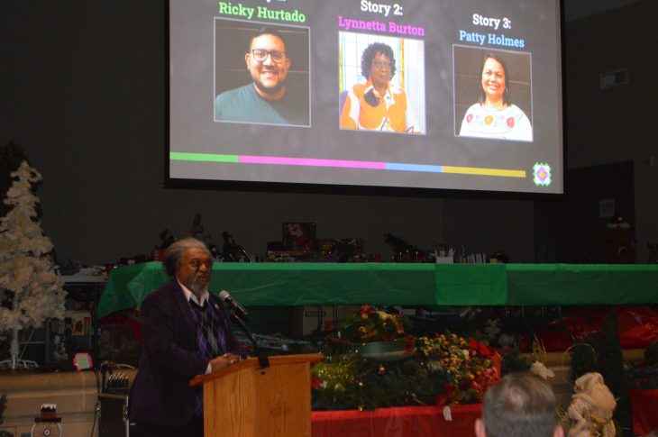 Man speaks at podium with three photos projected behind him.