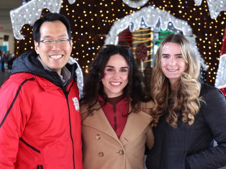 Young Do Kim of Elon University smiles with two sport management students.