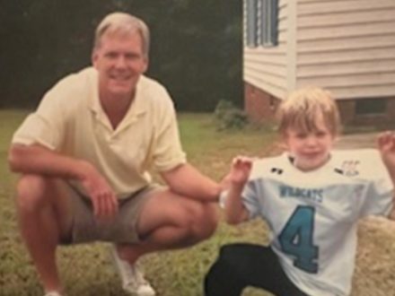 Man poses with boy wearing football jersey