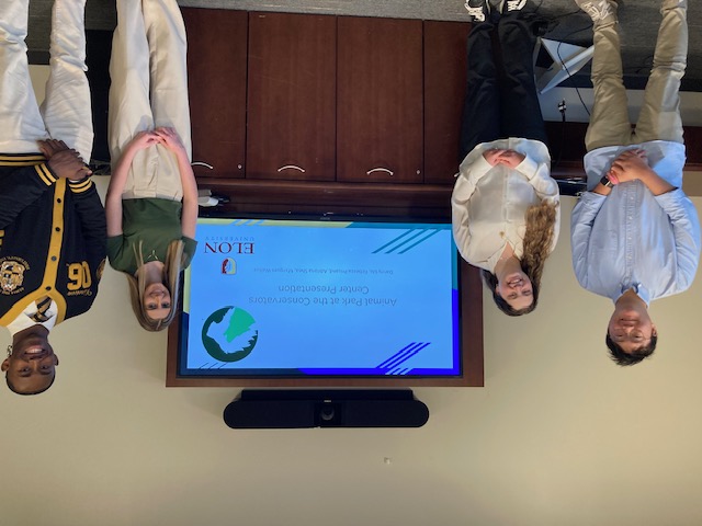 Four students pose for photo in front of a TV