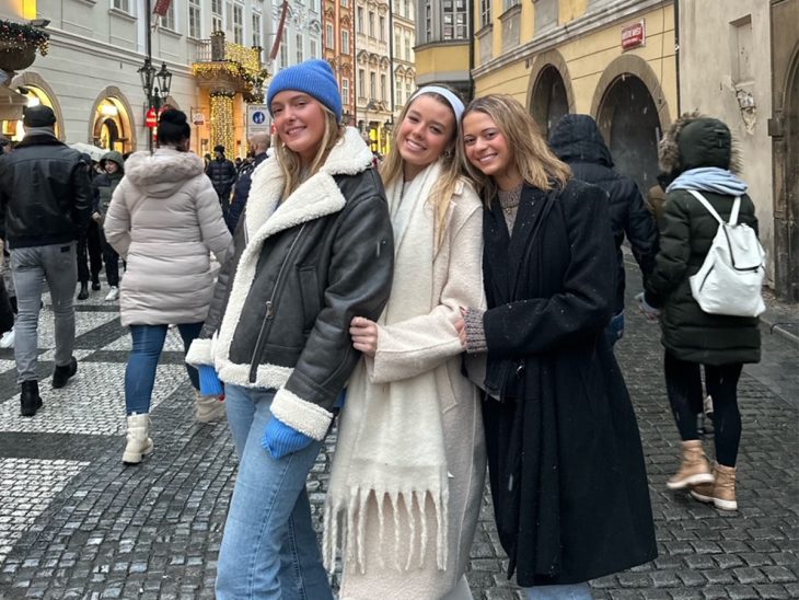 Three people pose on street