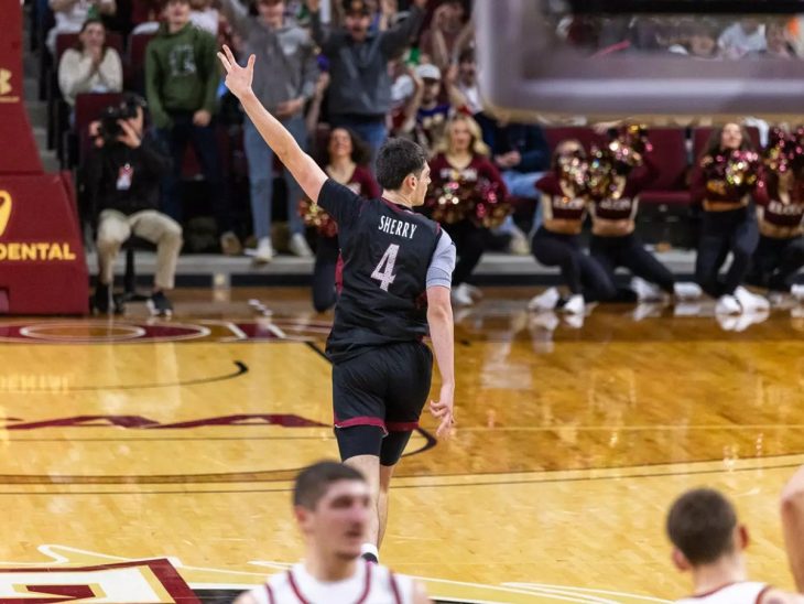 Basketball player wearing a jersey with 'Sherry' and the number 4 celebrating on the court, with spectators and cheerleaders in the background.