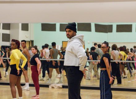 Auston Henderson teaches dance from Hamilton with fellow castmates to Elon students in a dance rehearsal studio. you can see students in mirrors as they perform a dance routine.