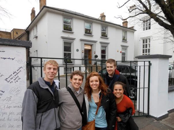 Group of people pose in front of a white house