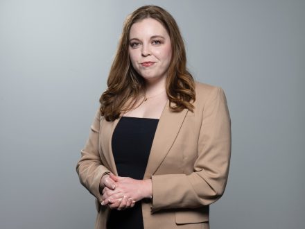 Professional portrait of Natalie Allison against a grey background.