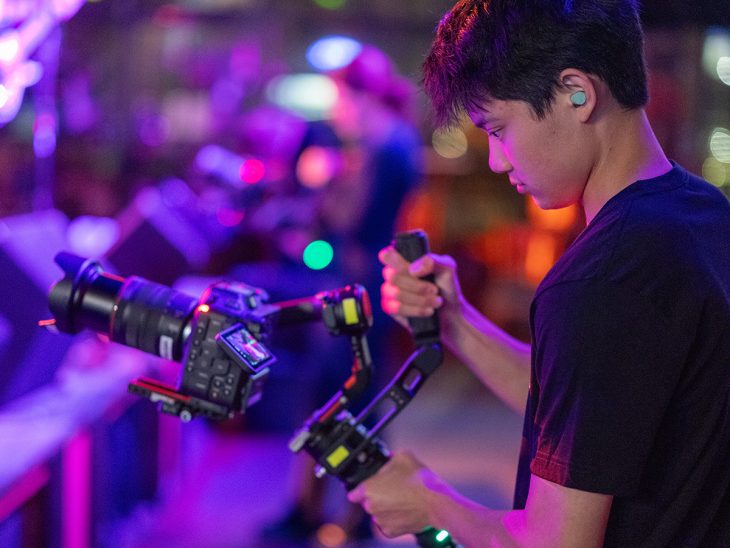 Colin Dorroh holds a video camera in a darkly lit room at an Elon eatery.