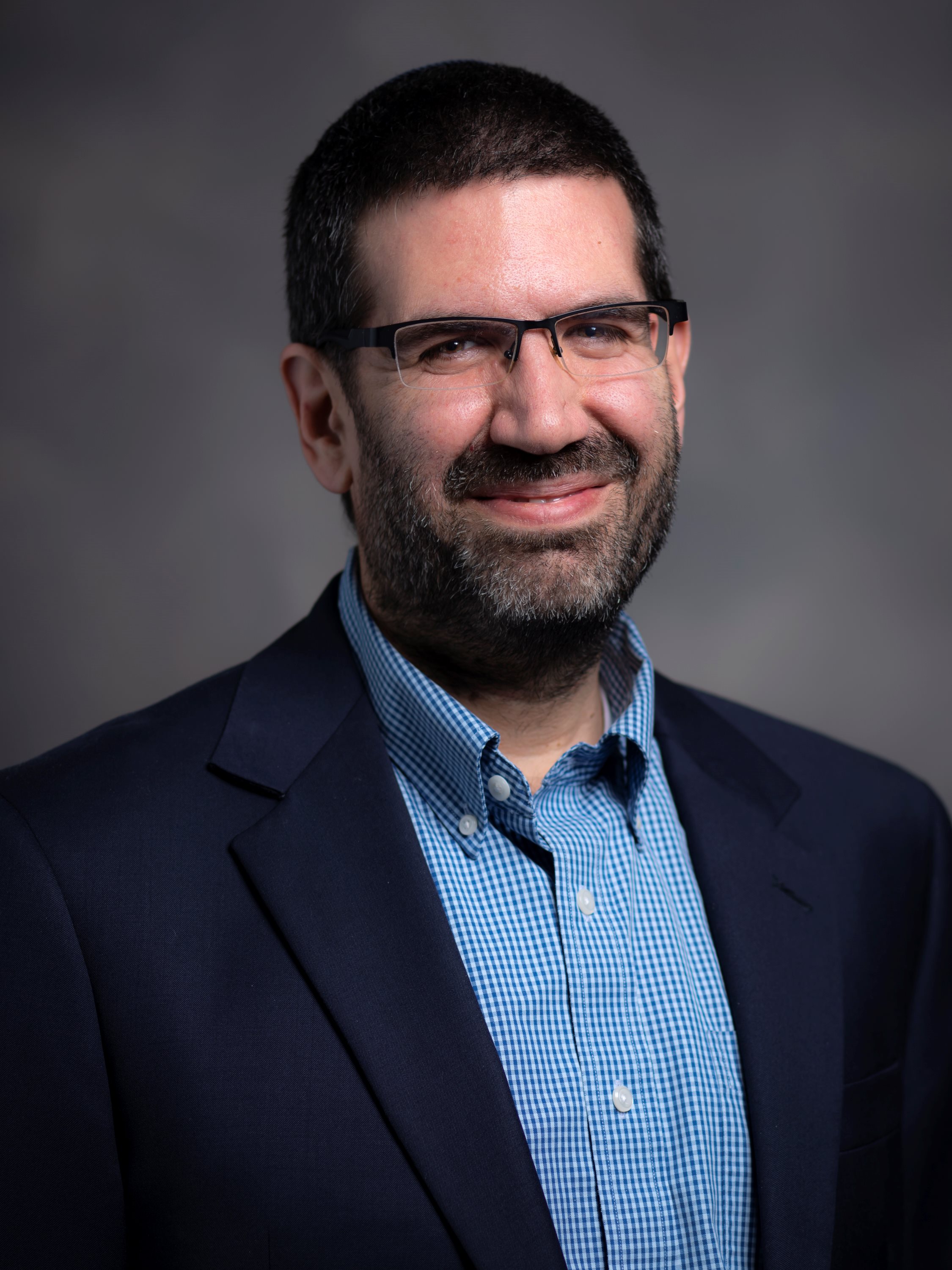 Directory portrait of Geoffrey Claussen wearing a navy blazer and blue button-up shirt